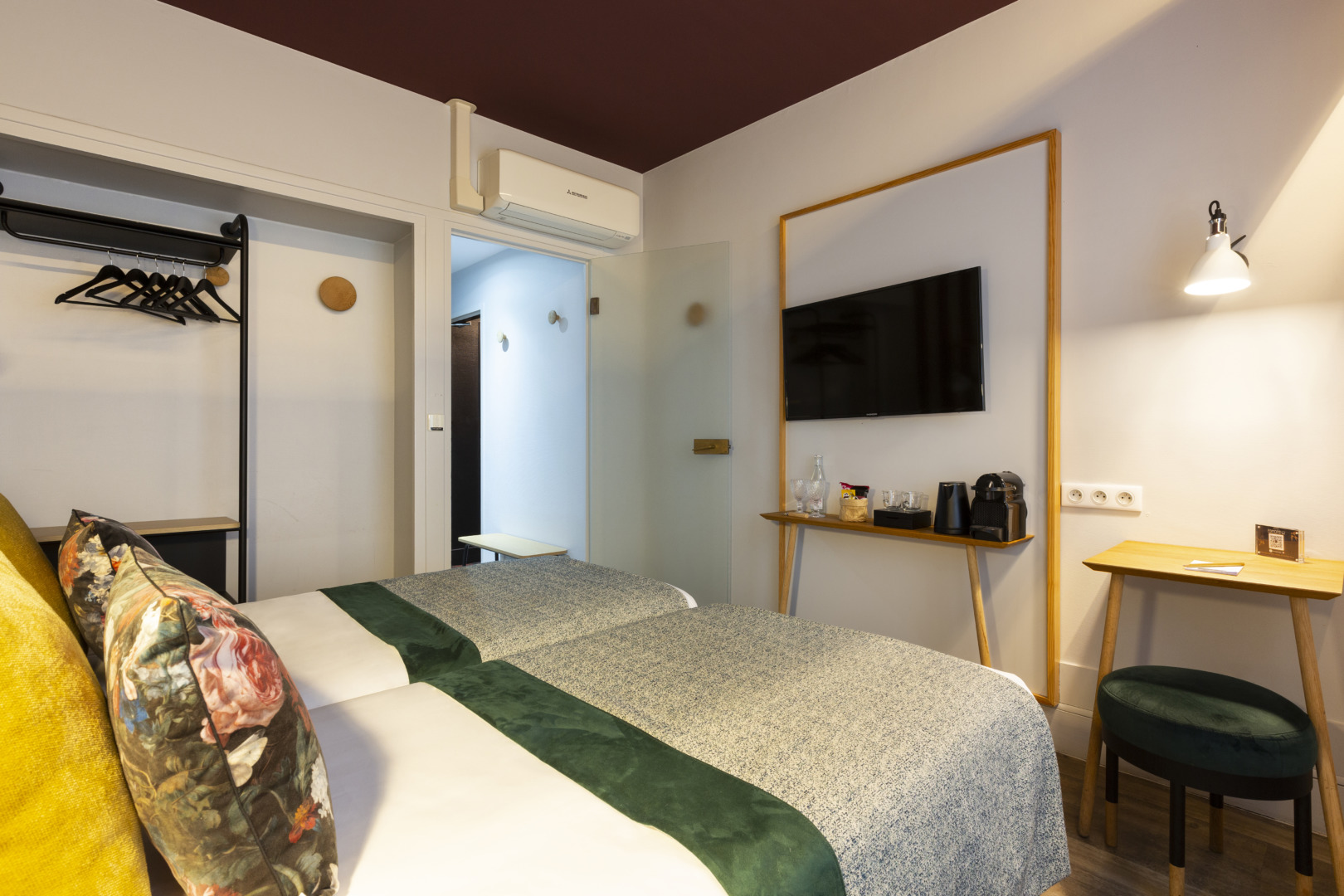 Zimmer mit 2 Einzelbetten: Kleiderstange, Milchglast&uuml;r, Wandfernseher, Kaffeemaschine, Schreibtisch und gr&uuml;ner Hocker